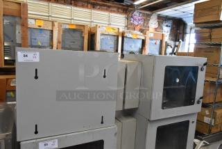 Two new BlackShields DC0300 white metal cabinets with clear front panels in a warehouse, auction tag visible.
