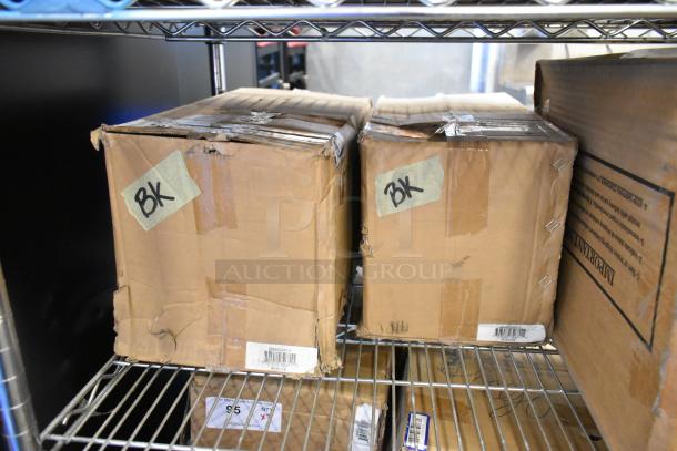 Two sealed boxes labeled "BK" containing Global 988870 forklift jack stands, 26,000 lb capacity, on metal shelves.
