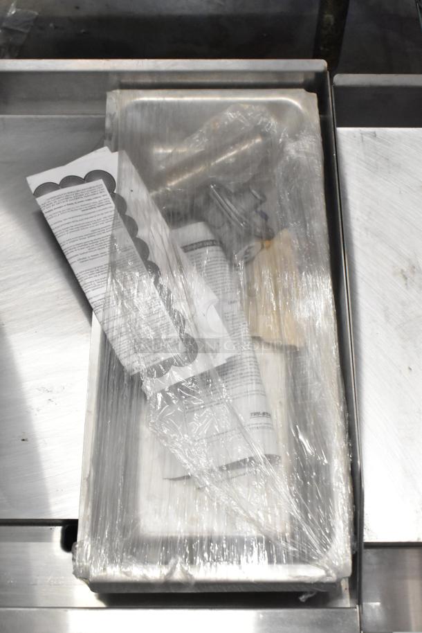 Brand new 2022 Tri Star TSGGM-18i stainless steel griddle, wrapped, with instruction manual visible.