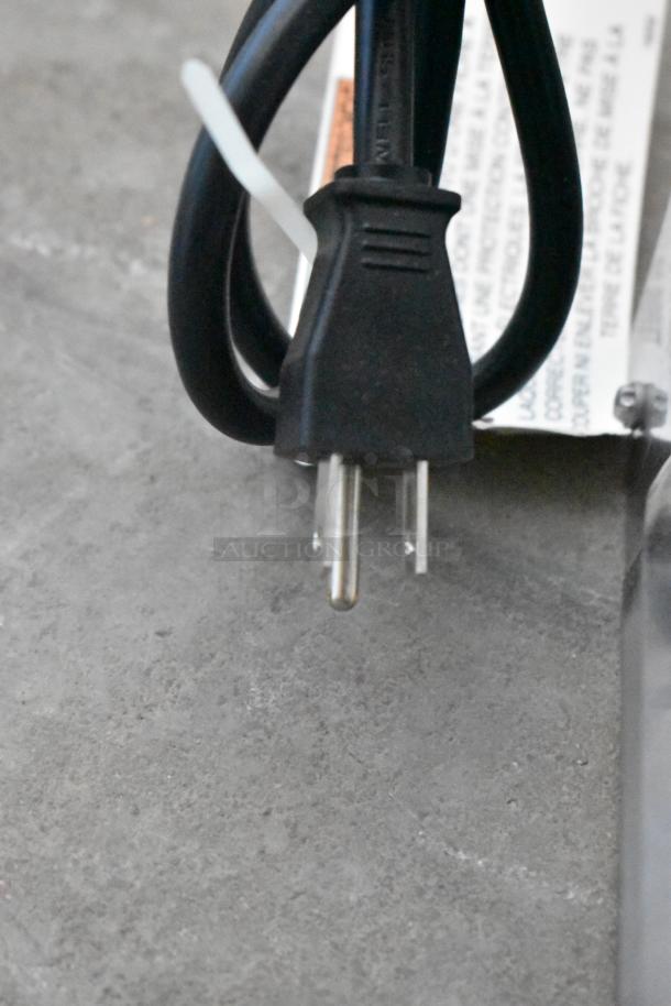 Alt text: Close-up of the power cord for a Henny Penny MPC-22 holding bin, showing a standard plug and attached tags.