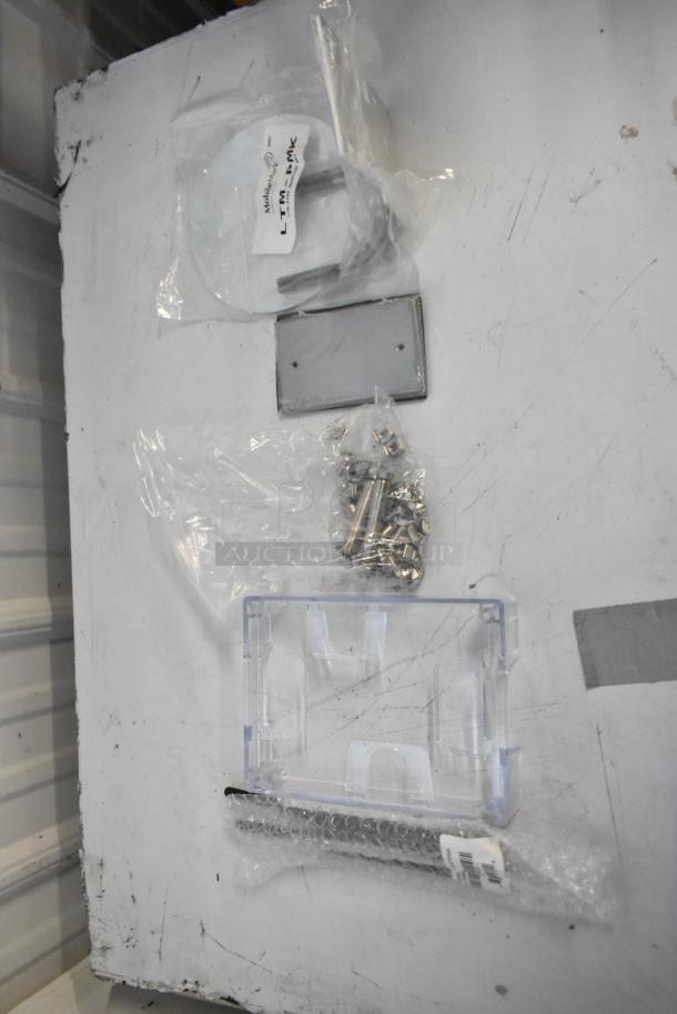 Brand new lot including pipe mounting kit, outlet box cover, screws. Items in clear plastic packaging on a table.