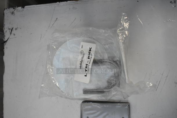 Brand new Mobile Mark LTM-PMK pipe mounting kit and outlet box cover in packaging, includes fasteners and instructions.