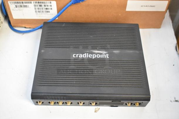 Cradle Point AER220 router, slightly worn, visible ports. Box of wires included in lot.