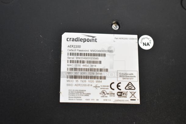 Cradlepoint AER2200 router label showing serial number, MAC address, and compliance codes on black background.