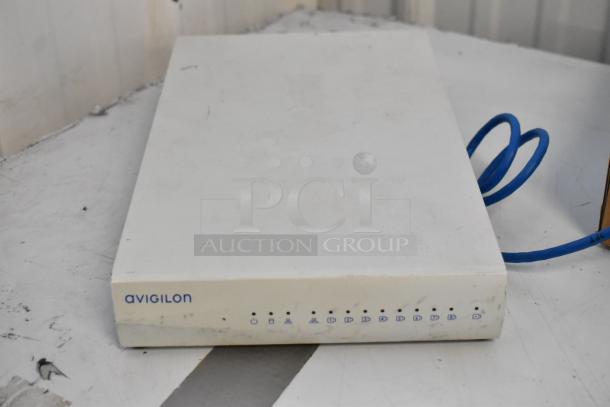 Avigilon Embedded NVR showing a white exterior with visible input ports and a blue cable, slightly used condition.