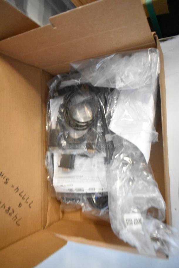 Cardboard box containing Cradle Point AER220, Avigilon Embedded NVR, and box of wires; mixed components visible.