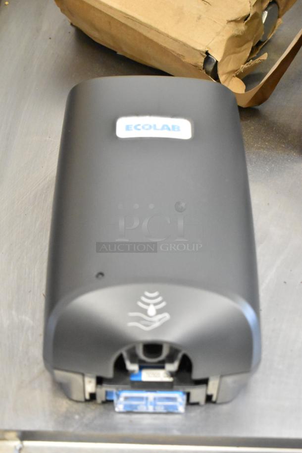 Brand new Ecolab Nexa Classic Touch-Free Dispenser, black, with logo and sensor icons, shown in original packaging.
