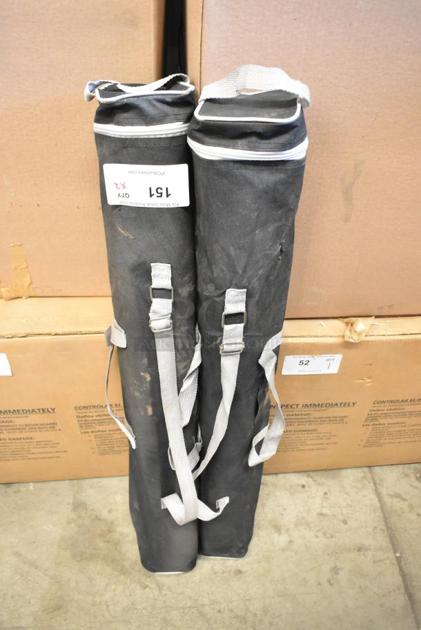 Two black soft bags with straps, containing one retractable easel. Visible tag reads "151" and "Qty x2." Good condition.