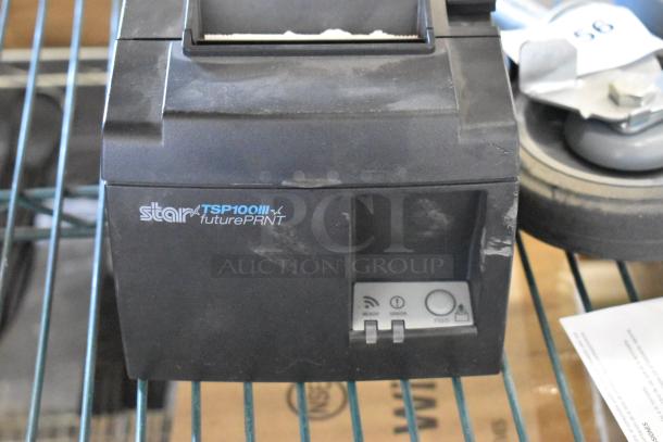 Star TSP100III futurePRNT receipt printer, visible wear, power and feed buttons, on metal shelving.