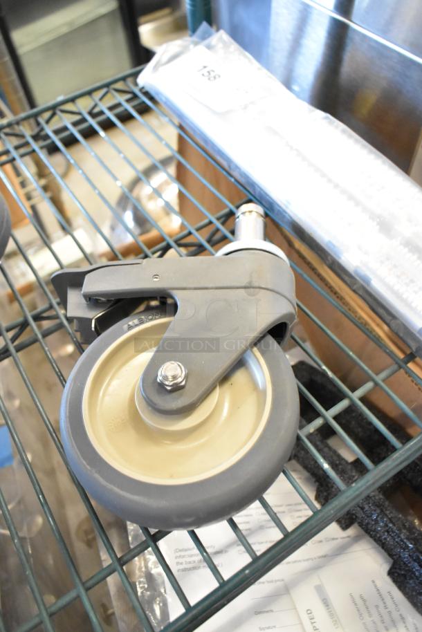 Lot of 4 commercial casters, gray plastic and metal construction, swivel mechanism, suitable for heavy-duty use.