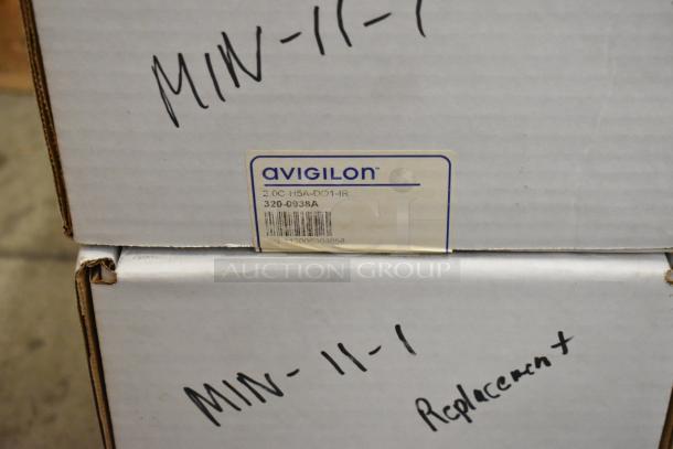 Boxes of Avigilon equipment, model 2.0C-H5A-D01-IR, labeled as replacements, shown in original packaging.