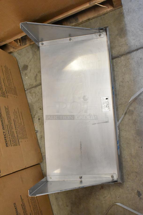 Brand new metal wall mount shelf with visible label detailing manufacturer. Securely packaged next to carton box.