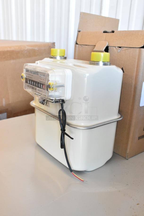 Brand new EKM Metering EKM-PGM.75 electric meter, displayed in box. Features analog display, wiring, and protective casing.
