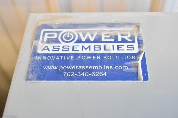 Brand new Power Assemblies gray metal box with blue label showing contact info. Clean, unused condition.
