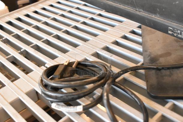 Dell U2412Mb monitor base on metal grate, visible power cable. Condition: used, slight surface wear.