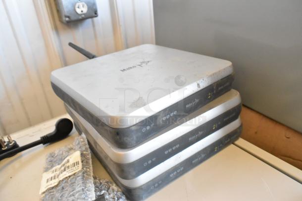 Lot of Mako routers, stacked, with visible power and network indicator lights. Light wear on surfaces, no cables included.