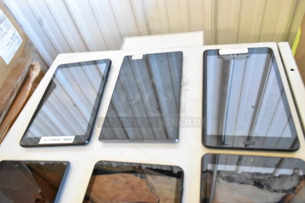 Six various tablets, including Samsung models, displayed on a white surface. Good condition, reflective screens visible.