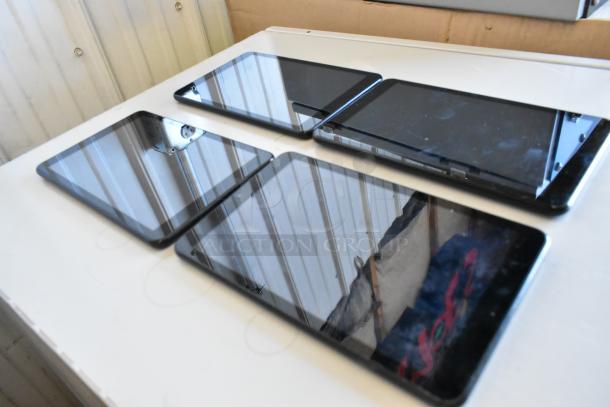 Four Samsung tablets displayed on a table, mixed models in good condition, with reflective screens and sleek black frames.