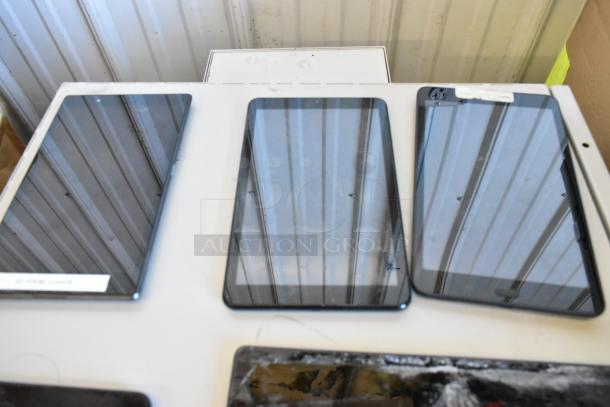 Six assorted tablets displayed on a table, various sizes and conditions, suitable for parts or repair. Tags visible.
