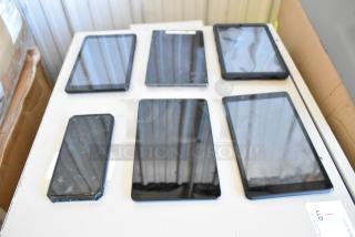 Six various tablets on a table, including at least one Samsung model. Moderate condition with some visible wear.