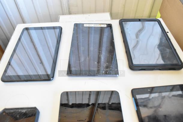 Six tablets displayed, including Samsung models. Varying conditions; one tablet shows a cracked screen. "Rebel Wings UE" label visible.