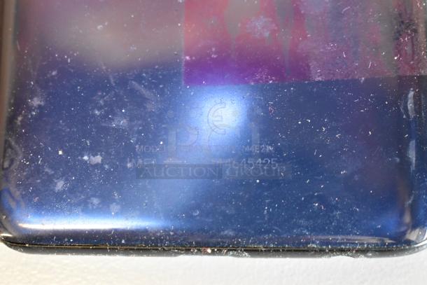 A close-up of a dusty tablet's back with model numbers and CE marking visible. Condition shows wear.