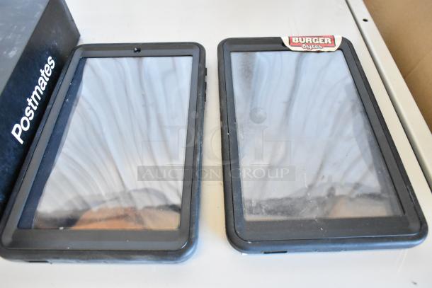 10 mixed tablets, including Samsung, various conditions. Visible stickers: "Postmates," "Burger Bytes." Black frames.