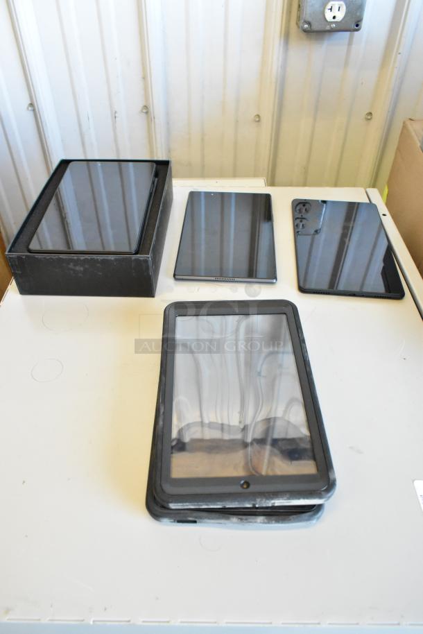 Five assorted tablets, including Samsung, on display. Some have visible wear, showing screens and edges. Mixed conditions.