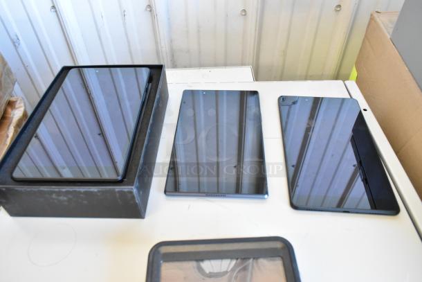 5 various tablets, including Samsung, on display. Items appear in good condition, screen reflections visible.