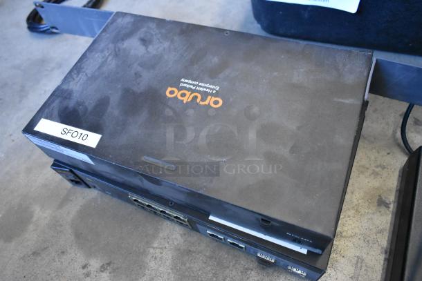 Lot of various items including a dusty orujo enterprise device with "SFO10" label, possibly used in networking setups.