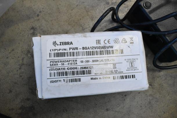 Lot includes Zebra power adapter with label details, gas detector, wires, and a Verizon corded telephone. Items in used condition.