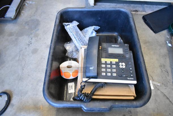 Lot of items including a Verizon corded telephone, gas detector, wires, and labels in a black bin, moderate condition.