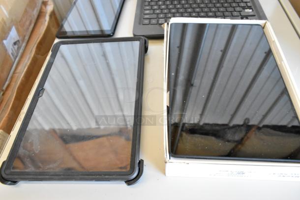 Four various tablets including Samsung, displayed on a table. Mixed conditions, some in cases. Ideal for bulk purchase.