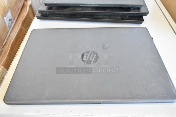 Stack of five laptops including Dell and HP, visible wear, includes branding, auction offers five times your bid.