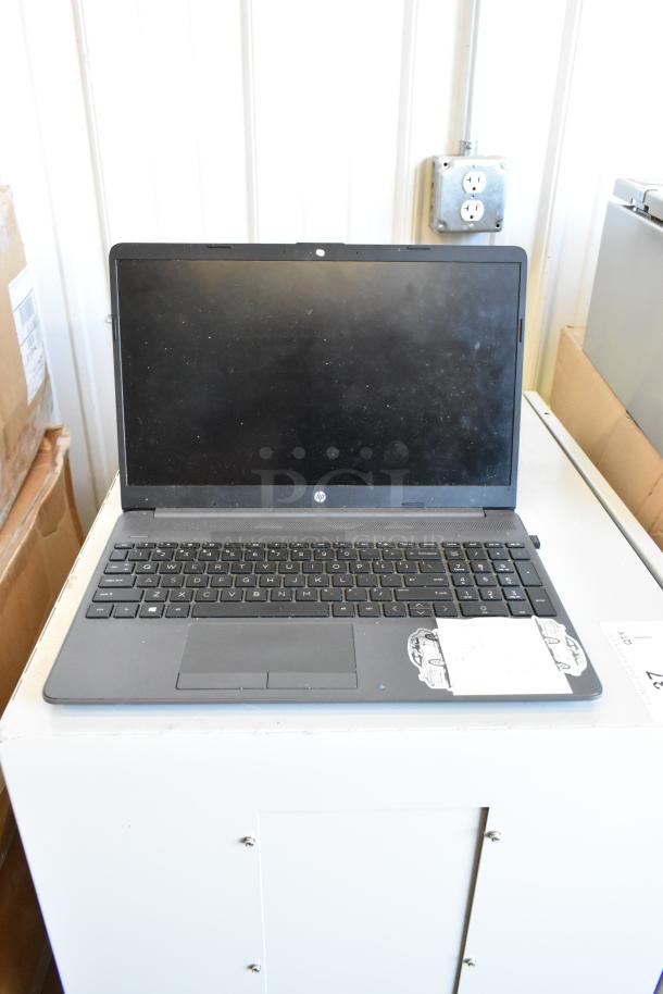 Grey HP laptop with visible wear, black keyboard, sticker on the palm rest, and auction tag. Part of a 5-laptop bundle.