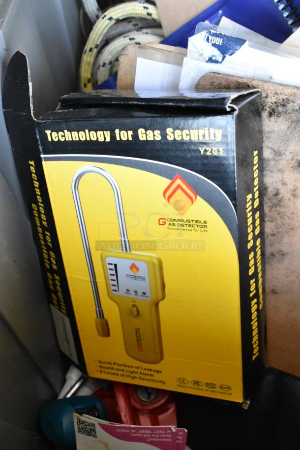 Poly bin containing a yellow gas monitor, Dymo LetraTag, and various items. Box labeled "Technology for Gas Security, Y201."