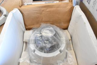 Brand new Avigilon camera in original packaging, covered in protective plastic. Box includes manuals and installation materials.