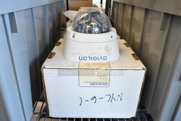 Brand new Avigilon 2.0C-H5A-D1-IR camera on box, dome covered in protective plastic, Avigilon logo visible.