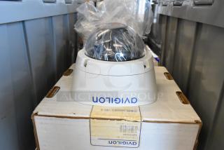 Brand new Avigilon 2.0C-H5A-D1-IR camera, dome style, on original packaging, showing model and serial numbers.