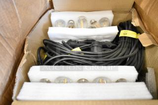 Brand new set of lights in box, includes bulbs and cords, secured with foam padding, yellow safety labels visible.