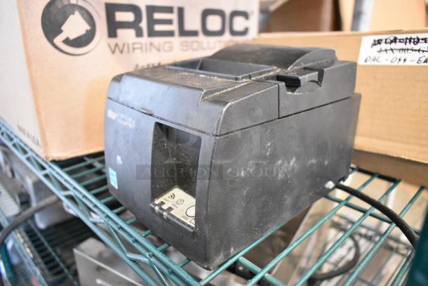 Star TSP100III Receipt Printer, 100-240V, 1 Phase, black, housed on a metal shelf. Slightly dusty exterior.