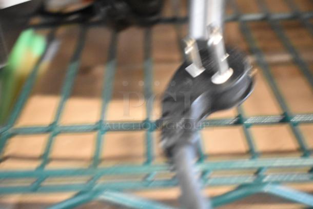 Blurry image of an electrical plug, likely part of the Vollrath Cayenne 58815 food warmer's power cord.