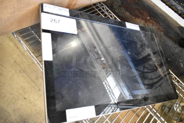 Flat-screen monitor with slight wear, auction tag 267 visible, on wire shelf. Black frame, reflections seen on screen surface.