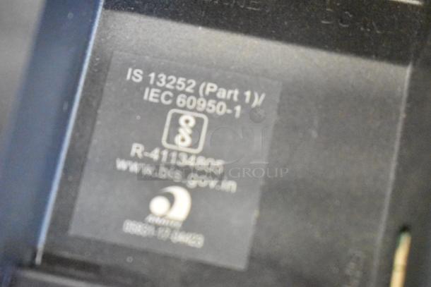 Tag on a monitor showing compliance with IS 13252 (Part 1)/IEC 60950-1 standards, includes www.bis.gov.in.