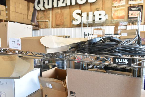 Lot of various wires on metal shelf, mixed condition. Includes power cords. Auction label: "PCAuctions.com 277 QTY VY2."