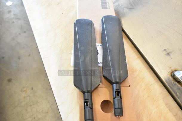 Two brand new antennas in black, packaged in a box.