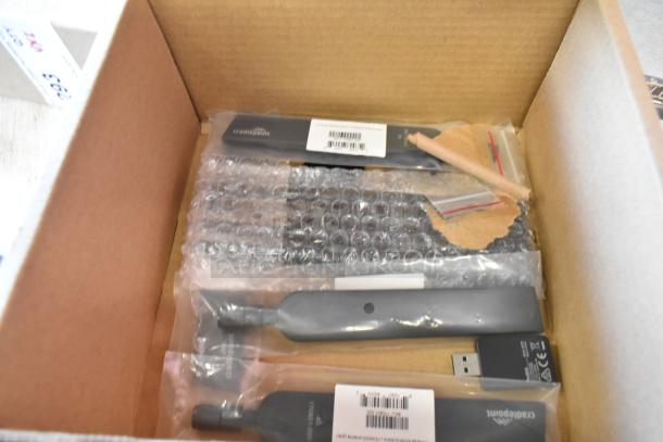 Two brand new Cradlepoint antennas with bubble wrap packaging, visible tags, and barcodes in a cardboard box.