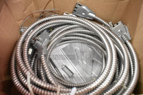 Brand new Reloc Fixture Cable coiled in box, featuring metallic protective exterior and attached connectors.