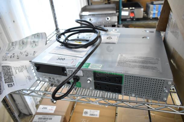 Metal unit with multiple power outlets, cables, and labels indicating caution and warranty. Appears in good condition on a metal shelf.