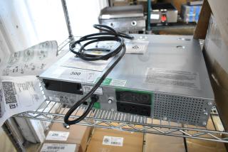 Metal unit with multiple power outlets, cables, and labels indicating caution and warranty. Appears in good condition on a metal shelf.